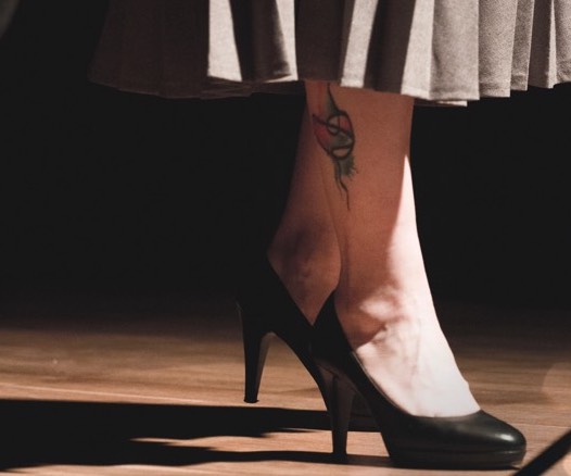 Mujer con tacones arreglada, tiene un tatuaje en la pierna