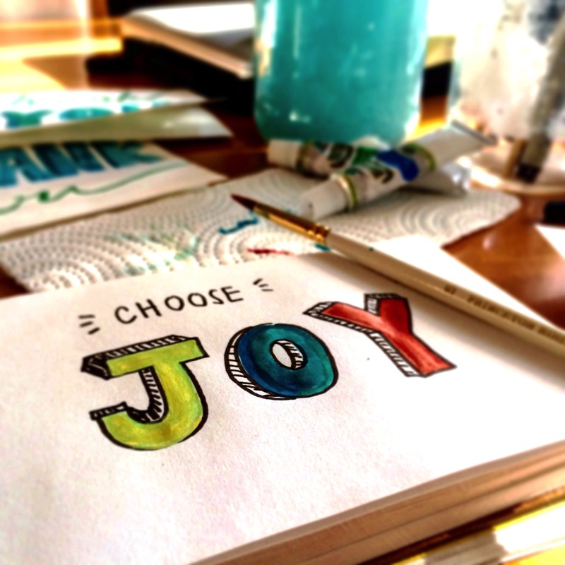 Escritorio con una libreta que dice: Choose Joy